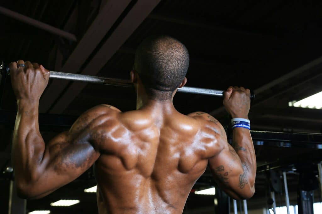 a man doing pull up in a gym for hypertrophy